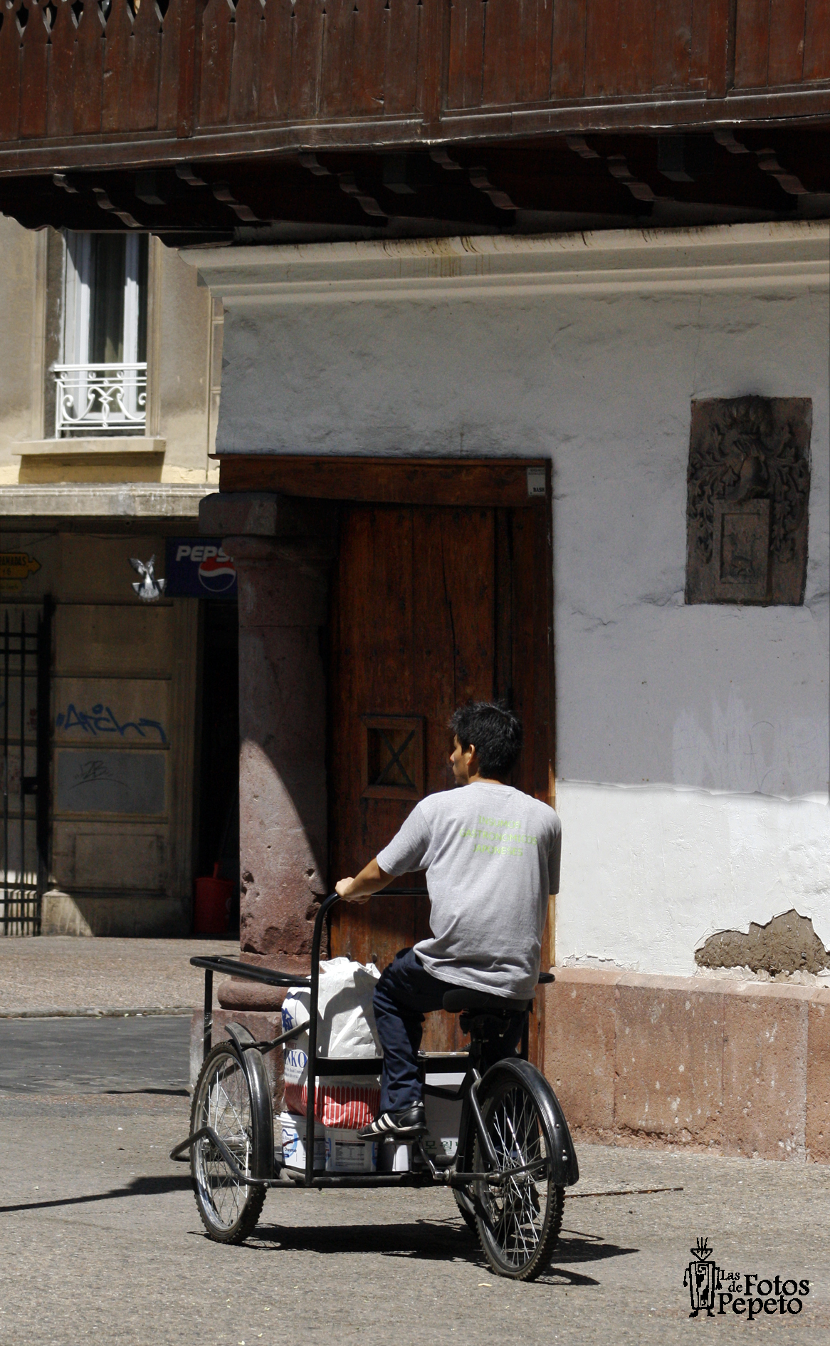 Muchacho en triciclo frente a la casa del Corregidor